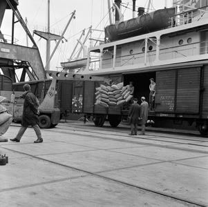 857536 Afbeelding van het beladen van een goederenwagen met balen, vermoedelijk in de Merwehaven te Rotterdam.